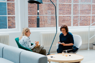 Gesprächspartner sitzen sich auf einer Couch an einem Tisch gegenüber